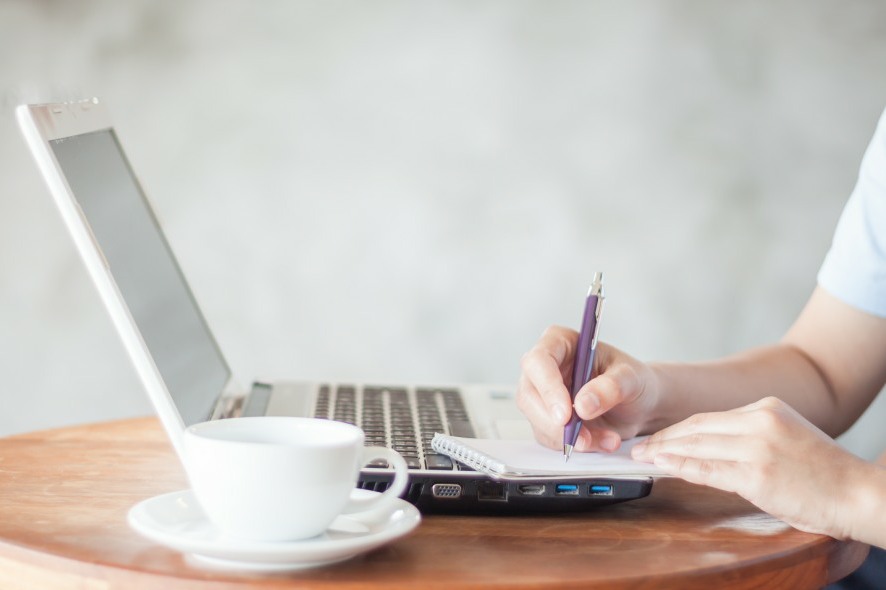 Woman writing on notepad in coffee shop